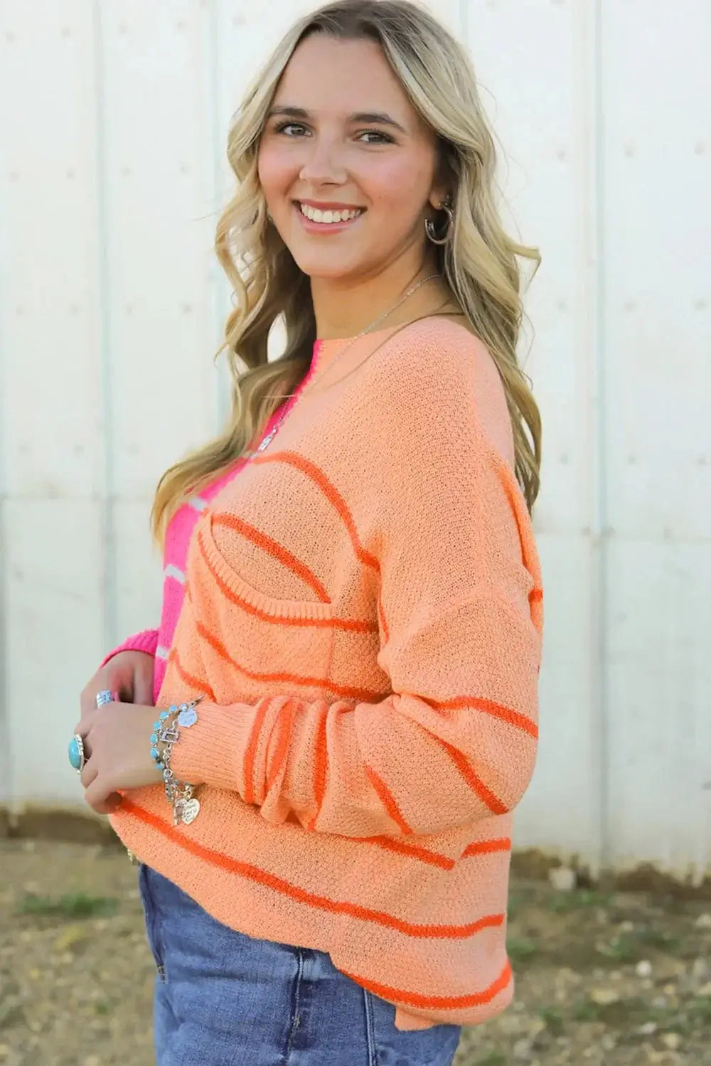 Model wearing Striped Pocketed Dropper Shoulder Sweater in orange and pink, showcasing its relaxed fit and cozy style.